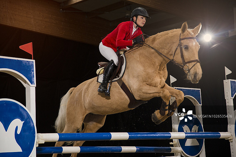 年轻女人和马一起跳过障碍图片素材