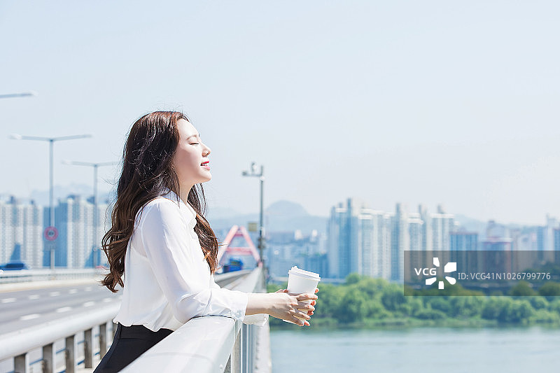 在桥上喝咖啡的女职员图片素材
