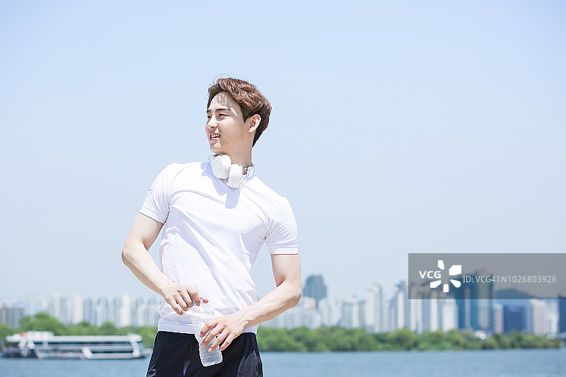 在公园喝水的运动装男人图片素材