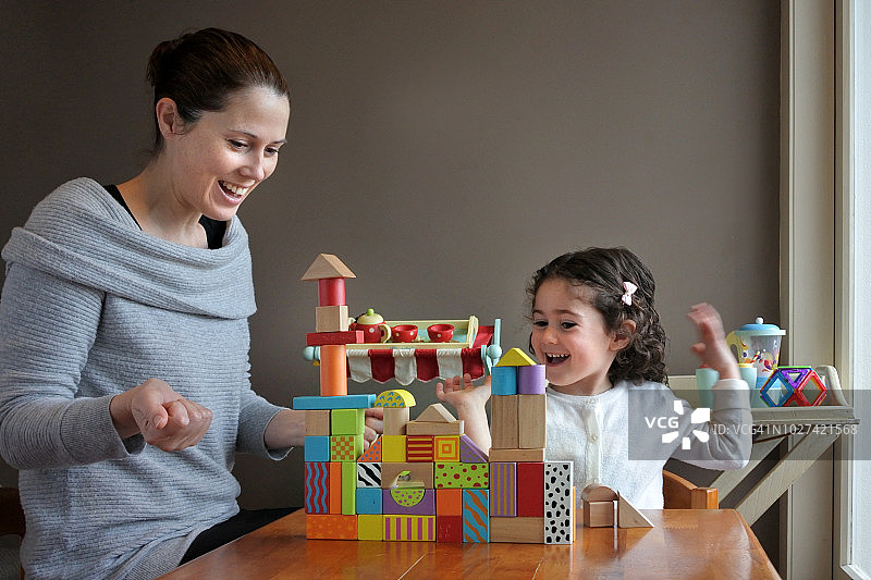 快乐的年轻女孩和她的母亲一起玩积木图片素材