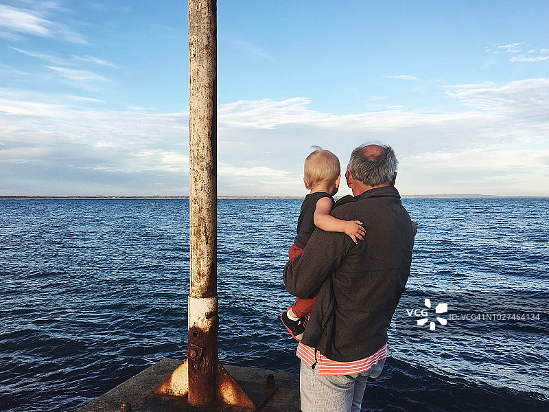 爷爷抱着孙子眺望大海图片素材