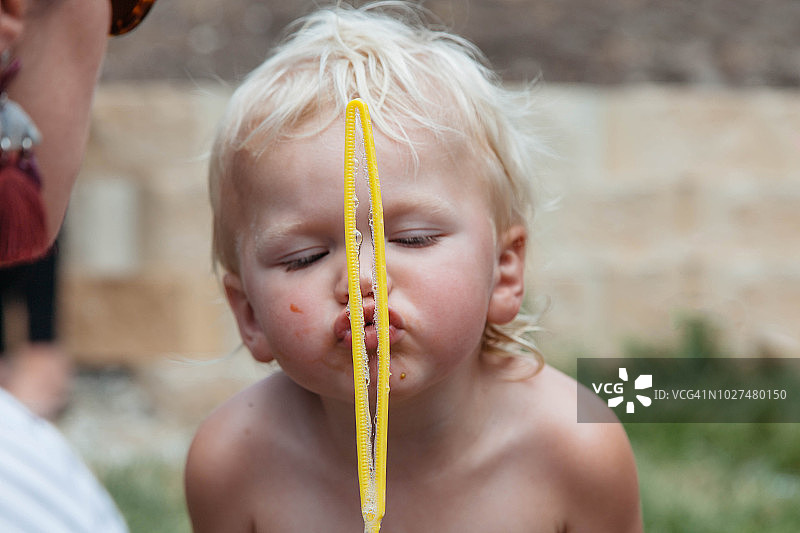 温暖的一天，幼儿在户外吹泡泡图片素材