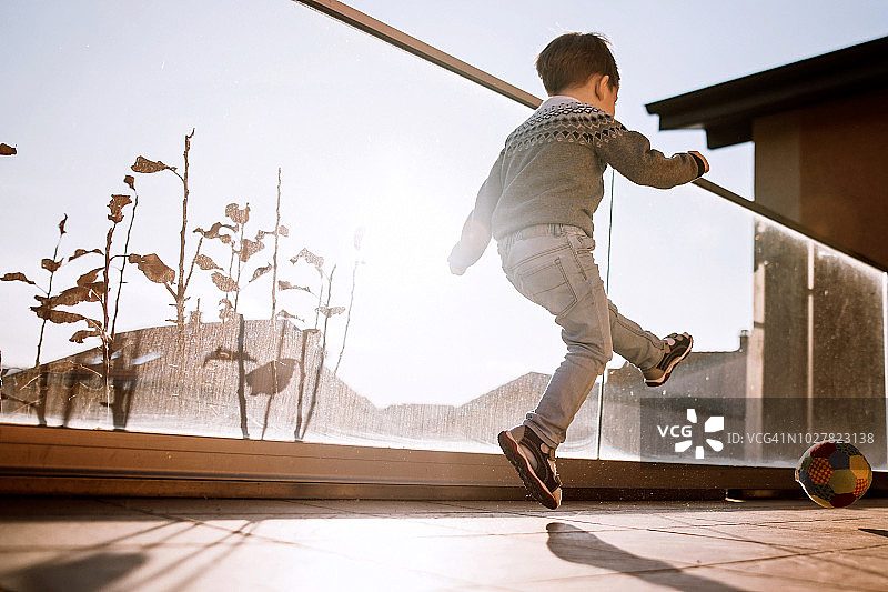 男孩在阳台上玩球图片素材