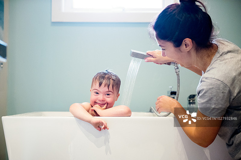 妈妈给患有唐氏综合征的可爱男孩洗澡图片素材