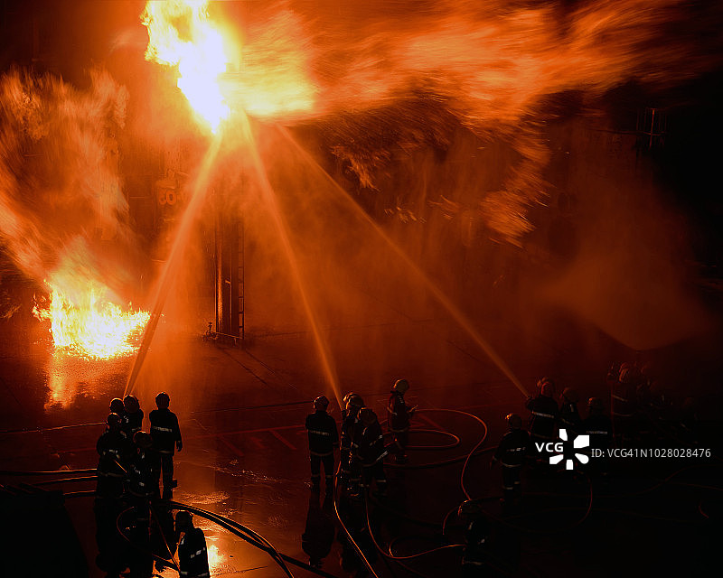 消防员帮助阻止工业工厂火灾的背面视角图片素材