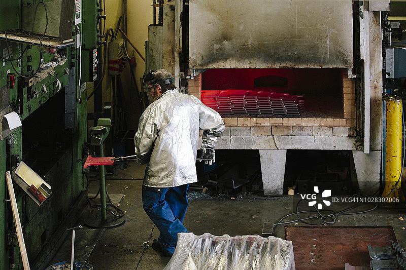 男蓝领工人在高炉和液压机旁使用热铁图片素材