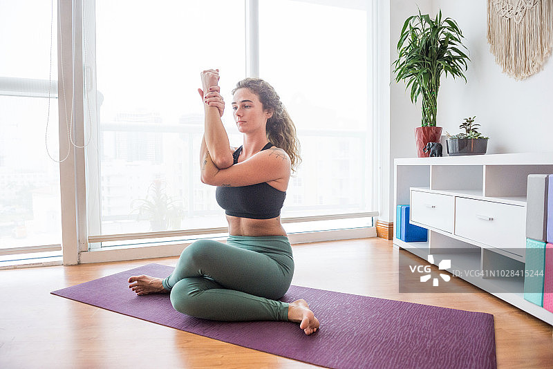 年轻女子在迈阿密家中练习牛面式瑜伽图片素材