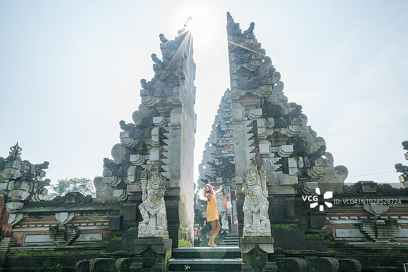 女人在巴厘岛乌布寺庙入口处跳舞，享受旅行乐趣图片素材