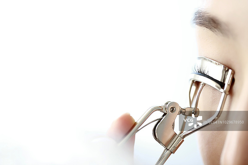 年轻女子使用睫毛夹特写图片素材