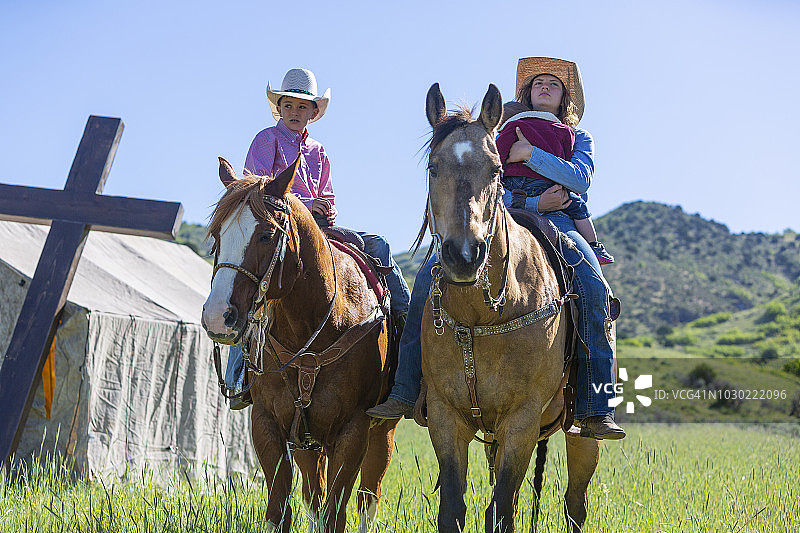 在教堂帐篷和十字架旁的田野里骑马的孩子图片素材