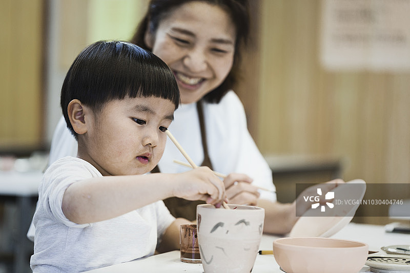 母子一起绘制陶器图片素材