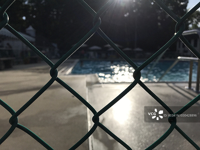 透过游泳池的栅栏看傍晚的阳光图片素材