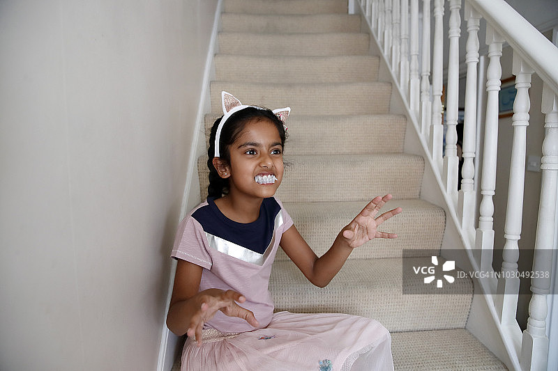 小女孩戴着玩具塑料牙齿做鬼脸图片素材