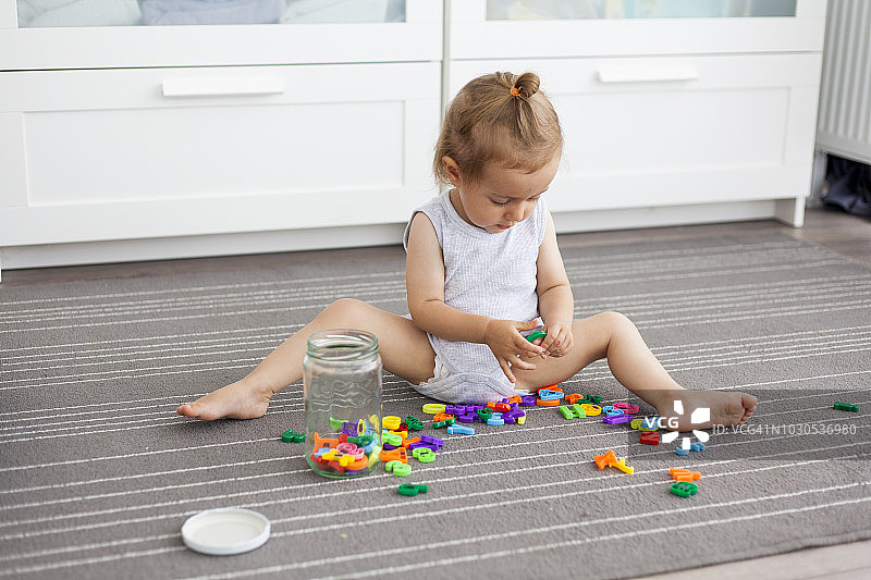 坐在地板上玩耍的可爱女孩图片素材