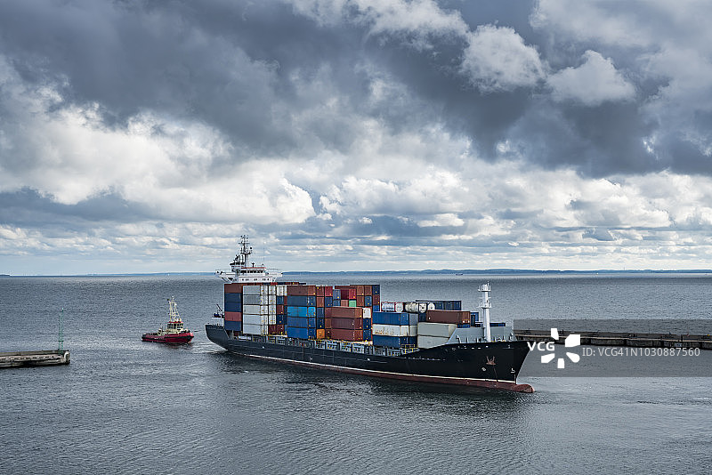 一艘拖船将集装箱船拖出港口图片素材