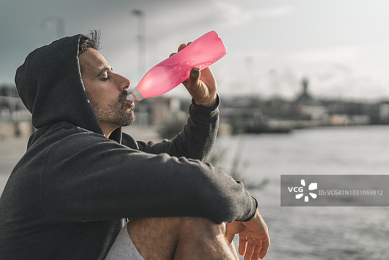 户外运动后在港口喝水的男人图片素材