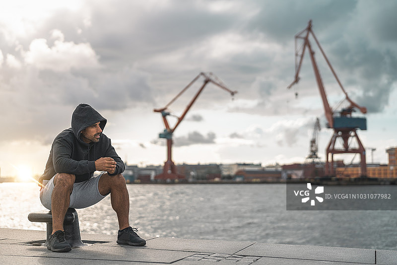 男人户外运动后在港口休息图片素材