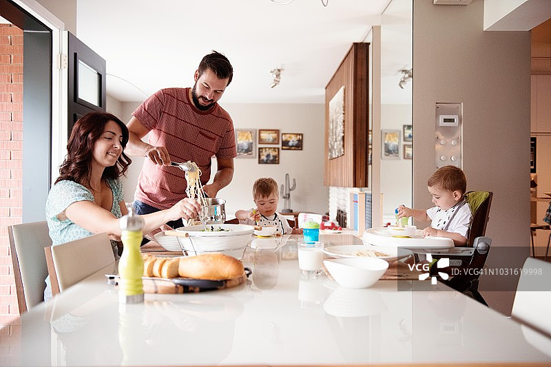 男人为唐氏综合征男孩及其姐妹和侄子提供意大利面图片素材