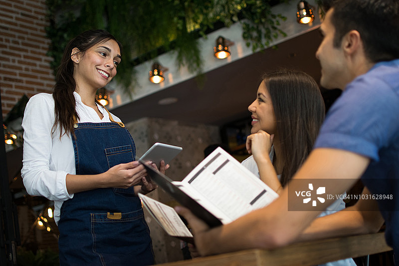 在酒吧点饮料的情侣与友善的女服务员图片素材
