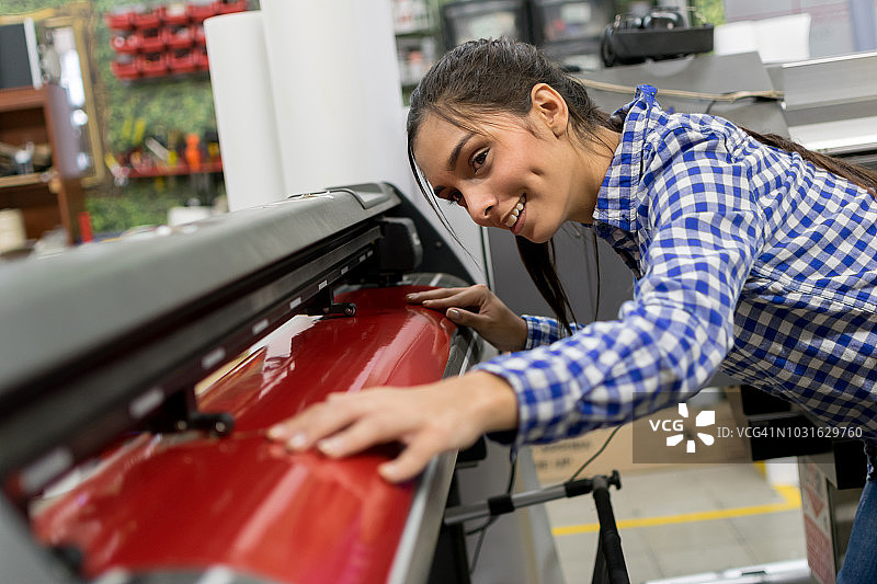 女子检查纸张是否正确放置在工业切割机中图片素材