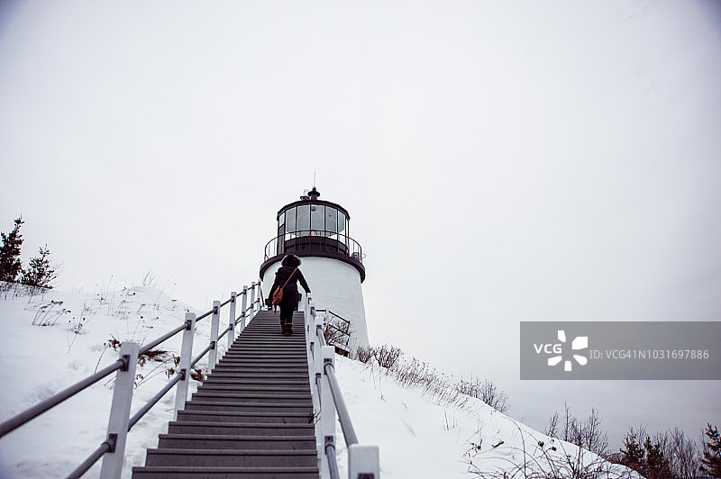 女人攀登猫头鹰头灯塔的台阶图片素材
