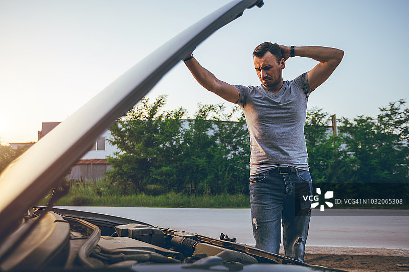 男子在一辆抛锚的汽车旁图片素材