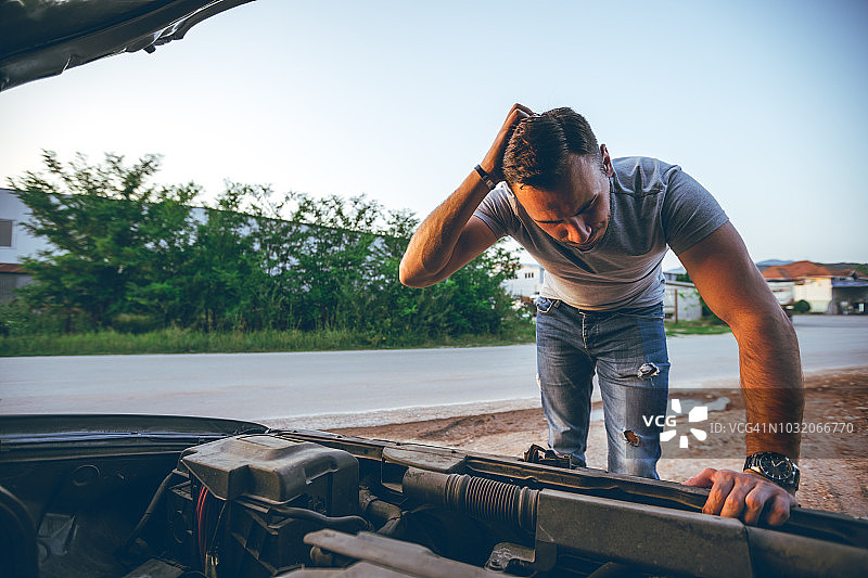男子在一辆抛锚的汽车旁图片素材