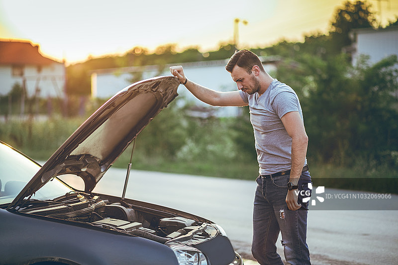 男子在一辆抛锚的汽车旁图片素材