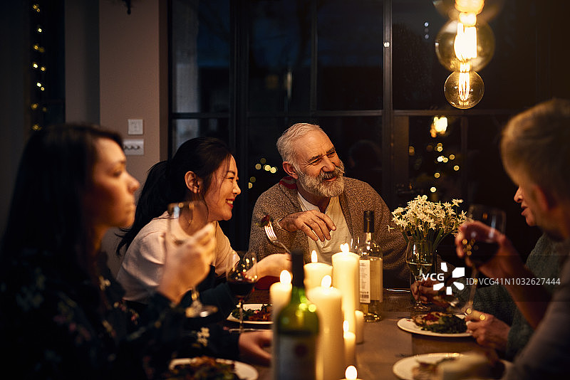 餐桌上快乐的客人们听朋友讲话并喝酒图片素材