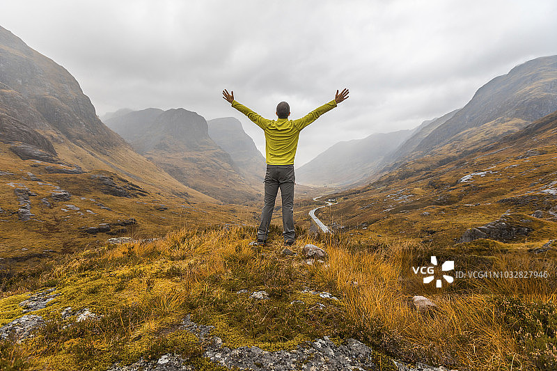 英国苏格兰：男子在格兰科附近苏格兰高地眺望三姐妹山图片素材