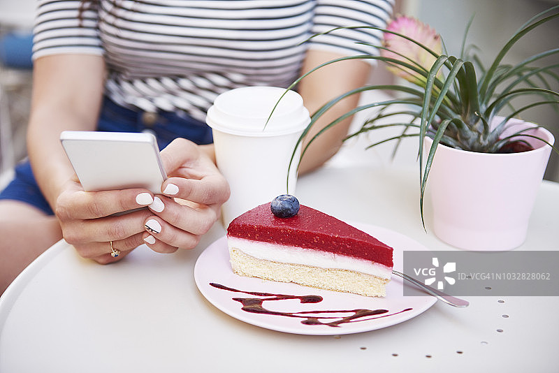 在咖啡馆用手机吃蛋糕的女人特写图片素材