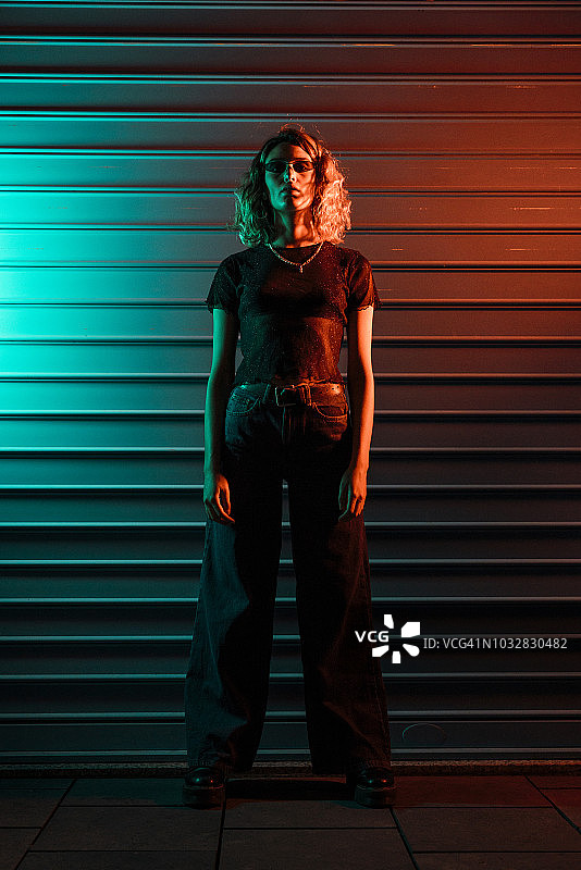 夜晚卷帘门前的时尚青年女性图片素材
