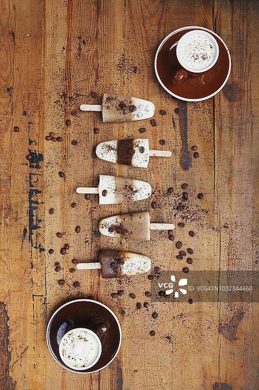 木质背景上的自制浓缩玛奇朵和拿铁玛奇朵冰棒，配咖啡豆图片素材