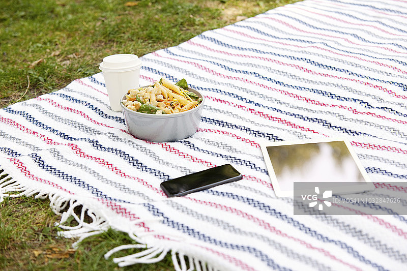 公园野餐：手机、平板、咖啡和沙拉图片素材