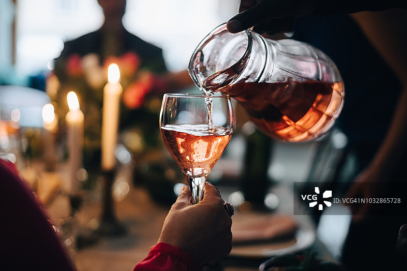 在晚宴上，男子为朋友倒饮料的裁剪图图片素材