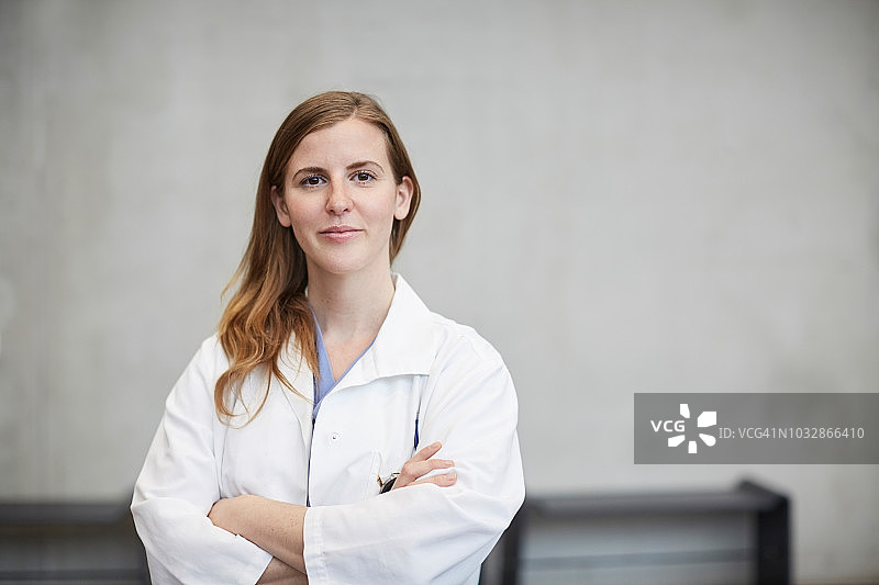 自信的中年女医生在医院靠墙站立，双臂交叉图片素材