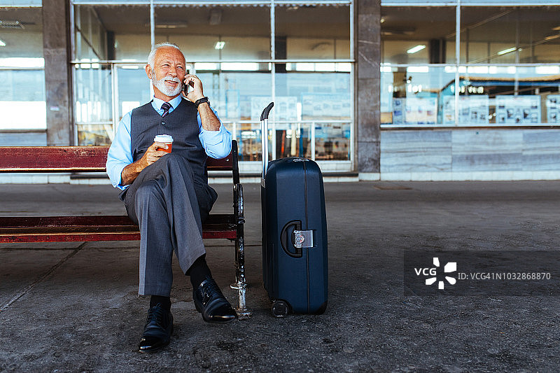 年长的商人在等火车时使用移动设备图片素材