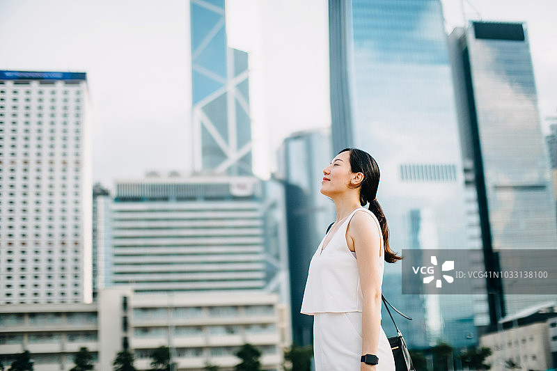 美女在金融区都市背景下闭目深呼吸图片素材