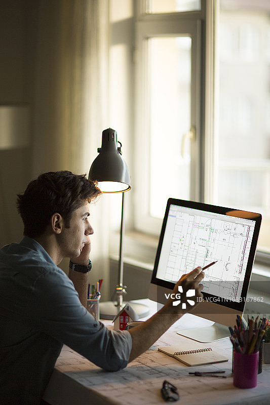 年轻工程师在蓝图纸上用笔检查建筑物结构，为会议展示做准备图片素材
