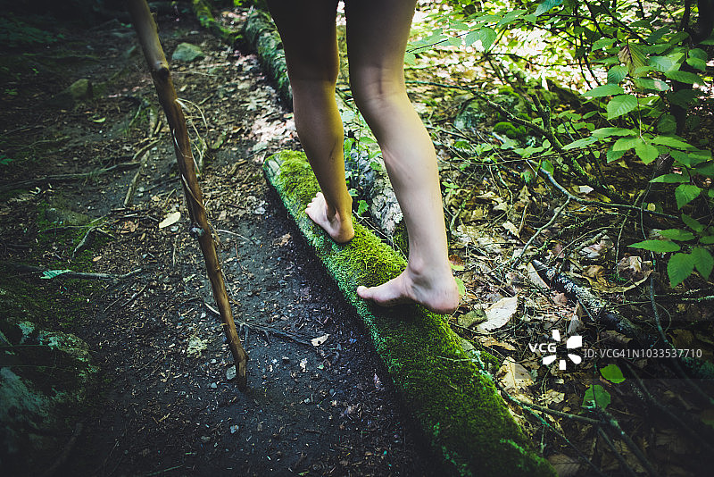 女孩在森林的苔藓木头上行走图片素材