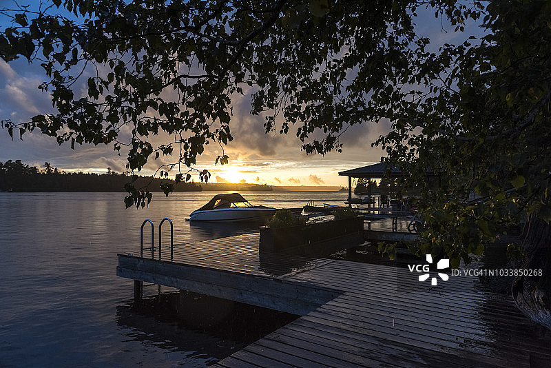 宁静湖面的日落，前景有码头和小船图片素材
