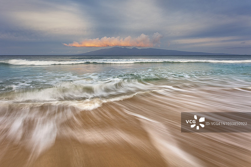 日出时柔和的海水在沙滩上延伸，可欣赏到莫洛凯岛的景色图片素材