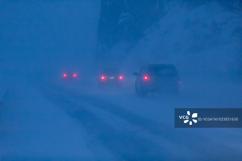 在漆黑的冬夜，西沃德高速公路上，汽车尾灯照亮了飞扬的雪花，特纳根海湾，基奈半岛中南部，阿拉斯加图片素材