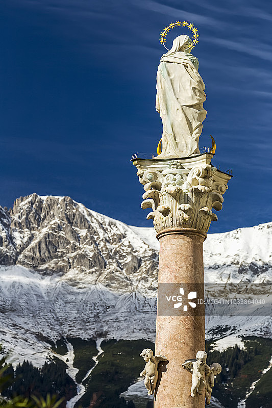柱子上带有光环的石像，背景是白雪皑皑的山脉和蓝天图片素材