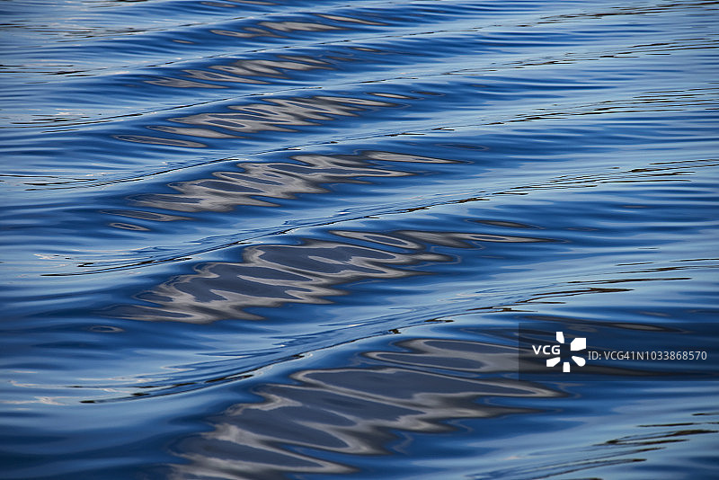 普吉特海湾船只尾迹上的天空、云彩和陆地的蓝色、黑色和白色倒影图片素材