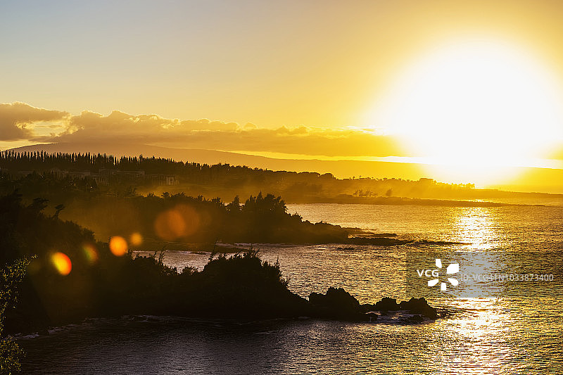 金色日落将黄色光芒投射在霍诺卢拉湾附近的海洋和海岸线上图片素材