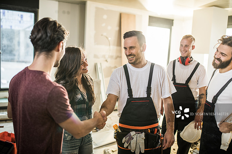 快乐的手动工人团队欢迎一对夫妇来到他们的公寓图片素材