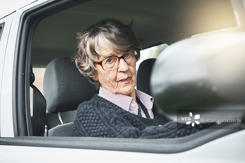 年长的女司机透过车窗对着镜头微笑图片素材