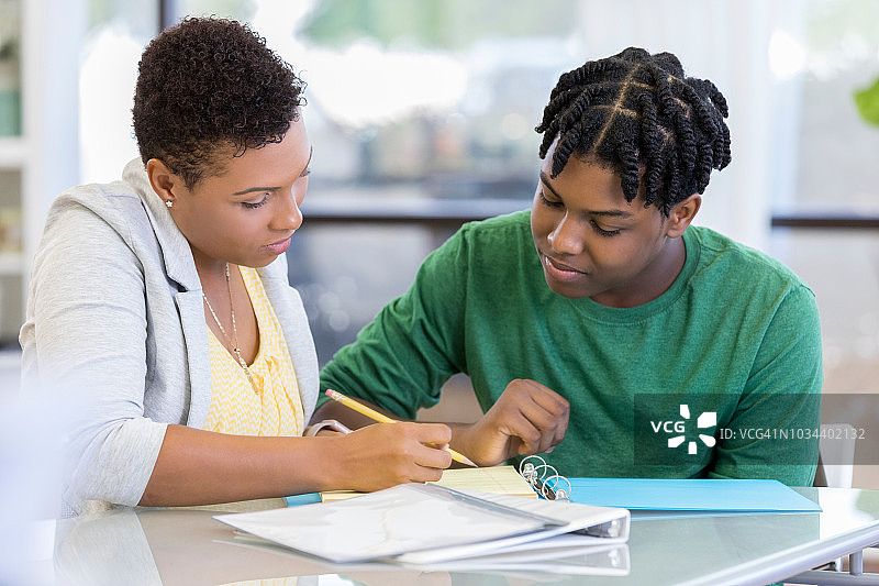 中年母亲辅导青少年儿子做作业图片素材