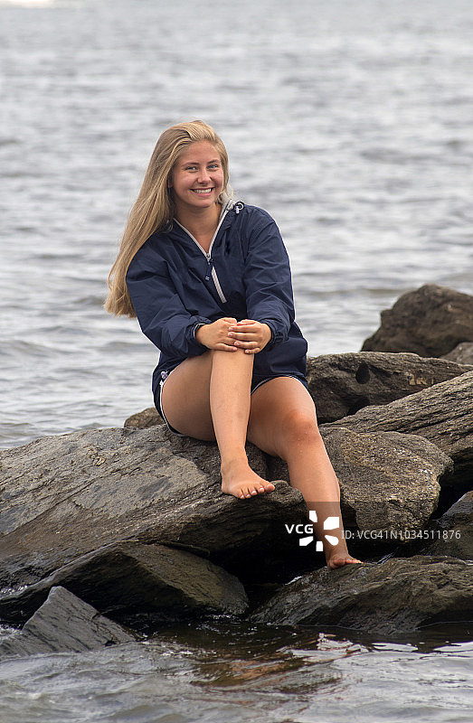 坐在岩石码头上的少女救生员图片素材